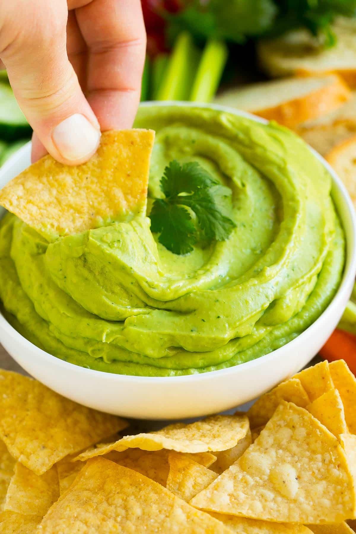 Ein Tortilla-Chip schöpft eine Portion Avocado-Dip auf.