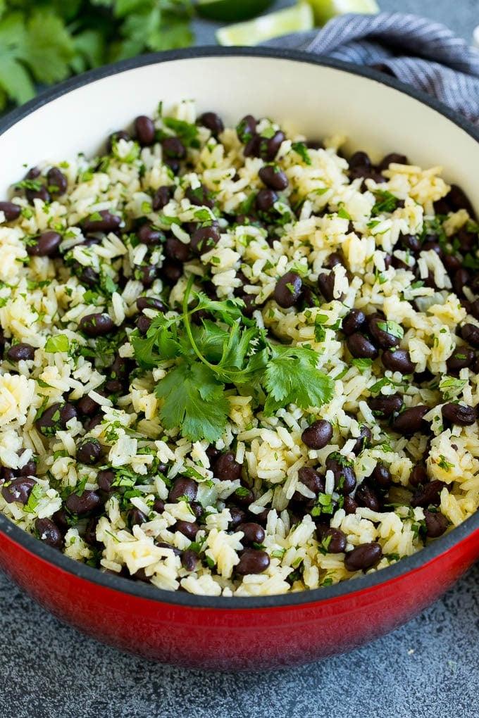 Rezept für Schwarze Bohnen und Reis | Kubanische Schwarze Bohnen | Bohnen und Reis #Bohnen #Reis #SchwarzeBohnen #Beilage #glutenfrei #Abendessen #ahurt Ein Topf mit schwarzen Bohnen und Reis, garniert mit Korianderzweigen.
