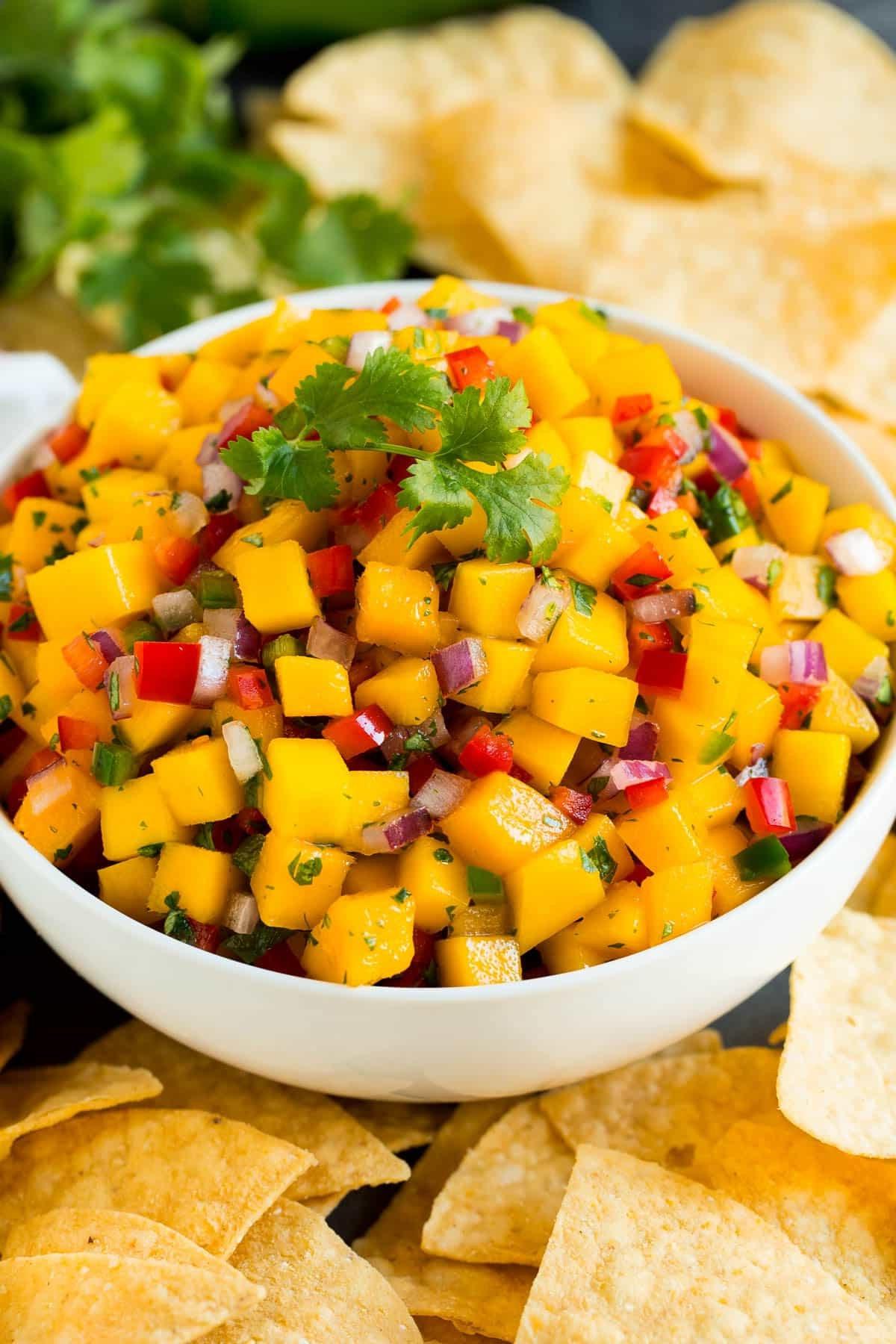 Mango Salsa Rezept 2 Eine Schale Mango Salsa serviert mit Tortilla-Chips auf einem hellen Hintergrund.