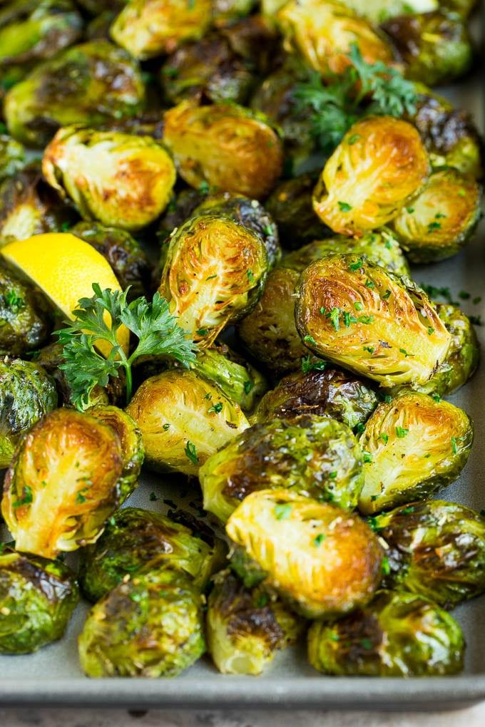Dieser knusprige Rosenkohl ist mit Olivenöl, Knoblauch und Gewürzen überzogen und wird bei hoher Hitze geröstet, bis er zart und goldbraun ist. Zarter Rosenkohl, knusprig geröstet und mit Zitronenscheiben sowie frischer Petersilie garniert.
