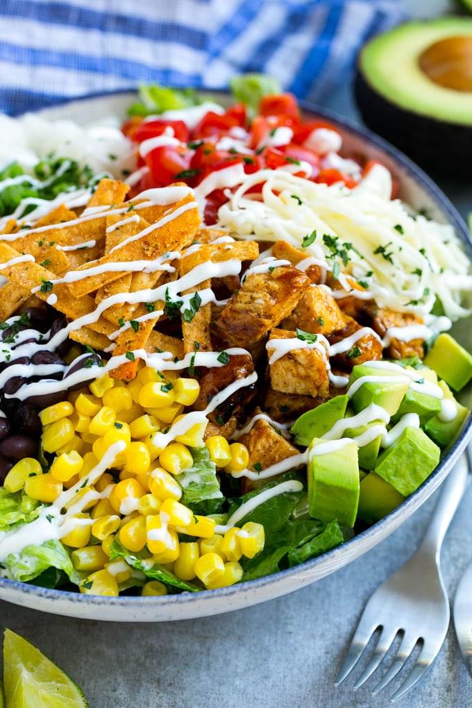 BBQ Hähnchen Salat Rezept | Gehackter BBQ Hähnchen Salat | CPK Copycat Rezept | California Pizza Kitchen Copycat Rezept | Hähnchen Ranch Salat #copycat #CPK #BBQchicken #chicken #salad #dinner #ahurt Eine Schüssel BBQ Hähnchen Salat, beträufelt mit Ranch-Dressing.
