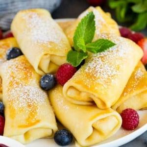Käse-Blintzes garniert mit Puderzucker und Beeren.
