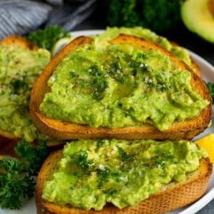 Ein Teller Avocado-Toast mit frischer Petersilie als Garnitur.