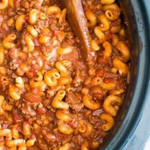 14 Slow Cooker Nudelrezepte 14 Ein Bild von Chili Mac in einem Slow Cooker mit einem Holzlöffel.