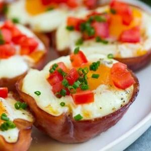 18 Schinkenreste-Rezepte 15 Ein Teller mit Schinken-Eier-Muffins, garniert mit gewürfelten Tomaten und Schnittlauch.