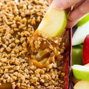 Eine Hand, die eine Portion Karamell-Apfel-Dip schöpft.