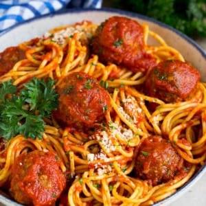 14 Slow Cooker Nudelrezepte 16 Eine Servierschüssel mit Crock Pot Spaghetti, garniert mit Fleischbällchen und geriebenem Käse.