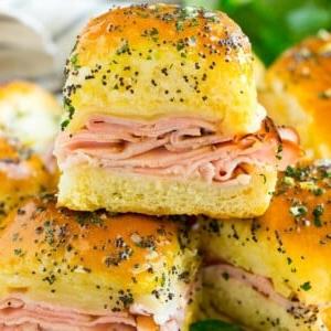 18 Schinkenreste-Rezepte 18 Schinken-Käse-Sliders auf einer Servierplatte, garniert mit Petersilie.