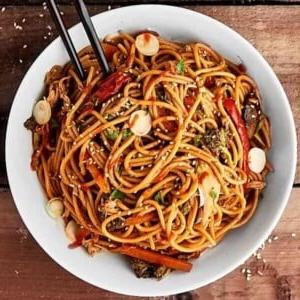 14 Slow Cooker Nudelrezepte 18 Ein Bild von Slow Cooker Lo Mein in einer weißen Schüssel mit schwarzen Essstäbchen.