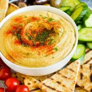 Eine Schale hausgemachter Hummus, serviert mit Pita und Gemüse.