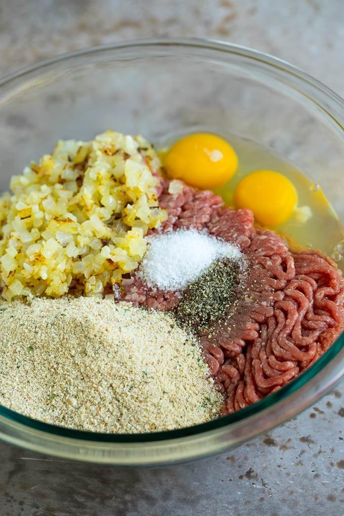 Hackbraten im Speckmantel 2 Rinderhackfleisch, Semmelbrösel, Eier, Gewürze und Zwiebeln in einer Rührschüssel.