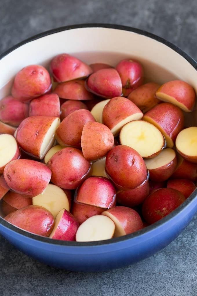 Diese Kartoffelpüree aus roten Kartoffeln sind zarte Kartoffeln, kombiniert mit Knoblauch, Butter und Gewürzen, um eine einfache und doch völlig befriedigende Beilage zu schaffen. Halbierte rote Kartoffeln in einem Topf mit Wasser.