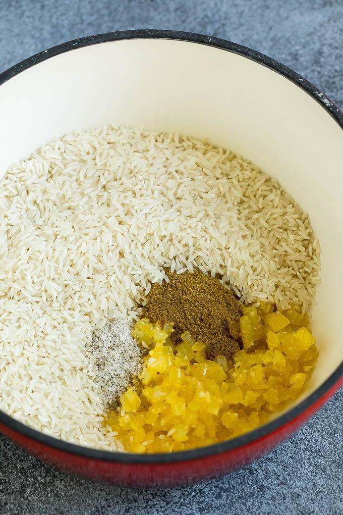 Rezept für Schwarze Bohnen und Reis | Kubanische Schwarze Bohnen | Bohnen und Reis #Bohnen #Reis #SchwarzeBohnen #Beilage #glutenfrei #Abendessen #ahurt Zwiebeln, Knoblauch, weißer Reis und Gewürze in einem Topf.