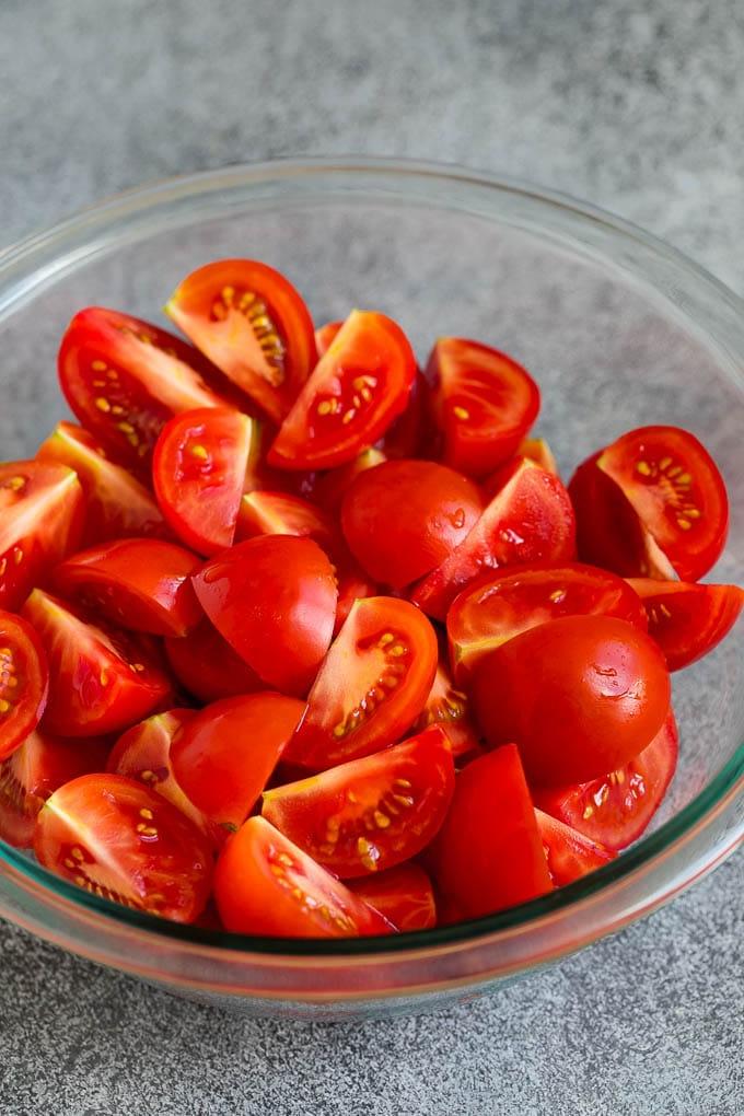Caprese Salad Recipe | Tomato Salad #salad #tomato #mozzarella #cheese #basil #caprese #summer #ahurt Geviertelte Tomaten in einer Schüssel.