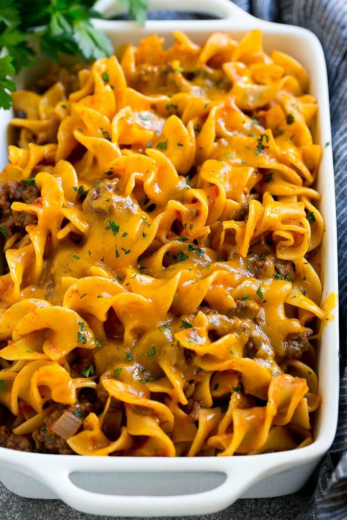 Hackfleisch-Nudel-Auflauf in einer Servierschale mit geschmolzenem Cheddar-Käse und Petersilie garniert.
