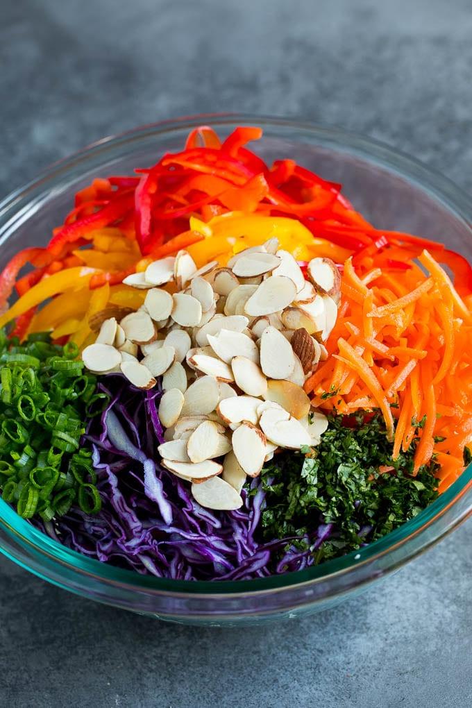 Asiatischer Krautsalat Rezept - Frische Zutaten Geraspelter Kohl, Gemüse und Mandeln in einer Schüssel.