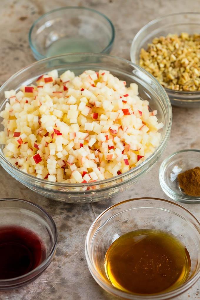 Dieses Charoset Rezept ist eine Mischung aus Äpfeln, Walnüssen und Honig, die zusammen eine süße Paste bilden, die ein wesentlicher Bestandteil jeder Passah-Mahlzeit ist. Schalen mit gehackten Äpfeln, Honig, Wein und Zimt.