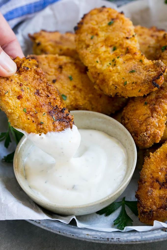Baked Fried Chicken Recipe | Oven Fried Chicken | Baked Chicken Fingers | Crispy Chicken Fingers #chicken #friedchicken #bakedchicken #ovenfriedchicken #chickenfingers #dinner #ahurt Ein Hähnchenfinger wird in Ranch-Dressing getaucht.