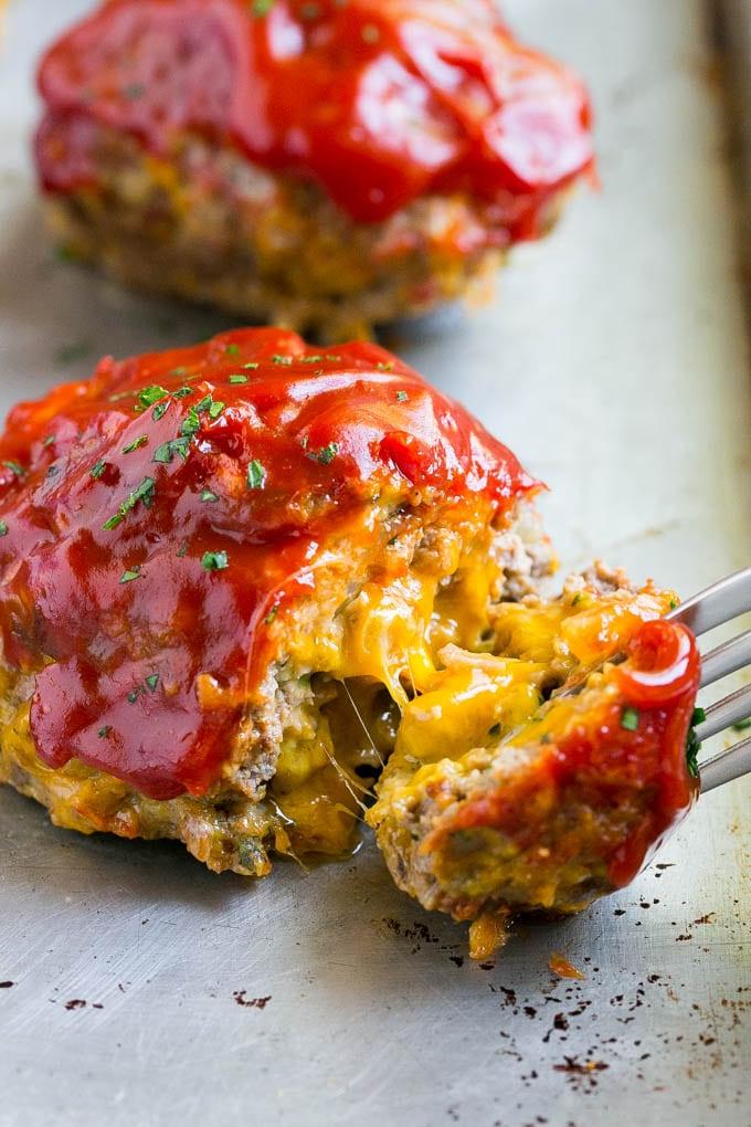 Ein Cheeseburger Hackbraten, von dem ein Stück mit einer Gabel abgenommen wird.