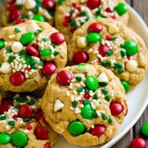 Ein Teller mit Christmas Monster Cookies, die mit M&M's, weißer Schokolade und Streuseln dekoriert sind.