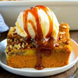 Ein Stück Kürbis-Dump-Cake, belegt mit Eiscreme und Karamellsauce.