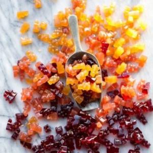 Ein Bild eines Metallschöpfers, der rote, orange und gelbe Gummibärchen hält.