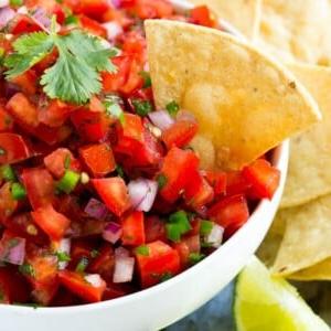 Eine Schale Pico de Gallo mit einem Tortilla-Chip darin.