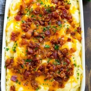 Kartoffelauflauf mit allem Drum und Dran, belegt mit geschmolzenem Käse, Speck und Kräutern.