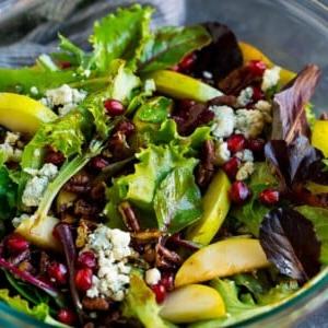 Eine Schüssel Birnensalat mit Granatapfel, Blauschimmelkäse und kandierten Pekannüssen.