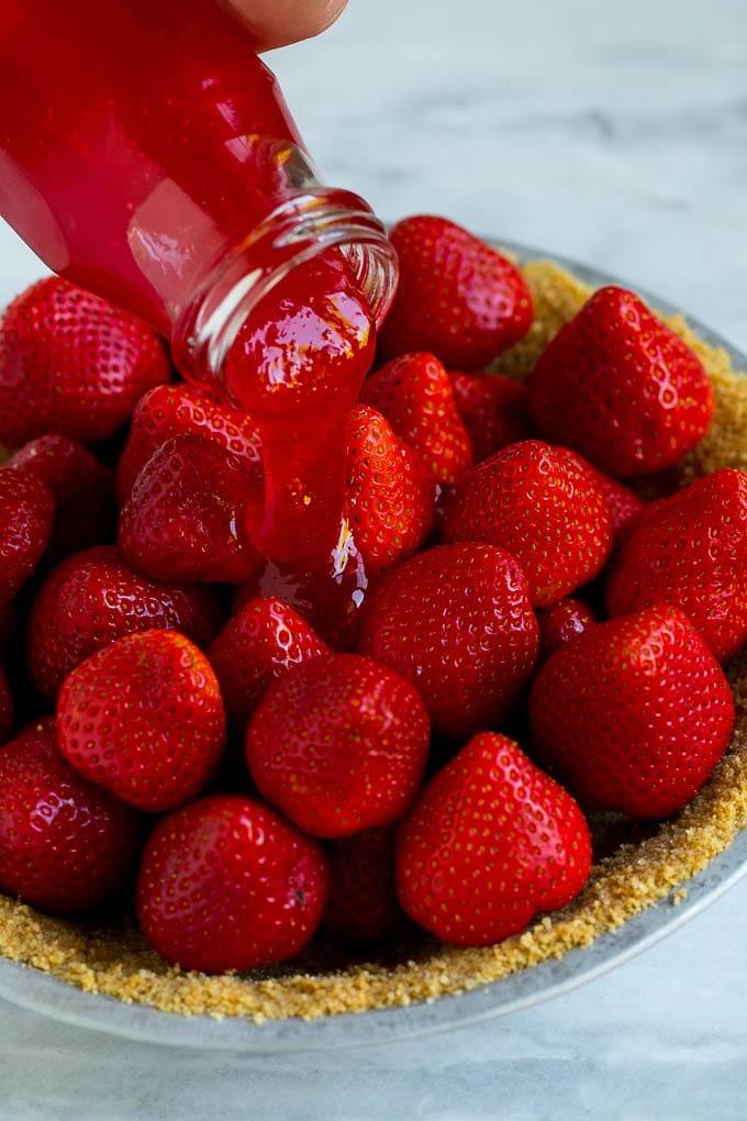 No-Bake Erdbeerkuchen Rezept | Frischer Erdbeerkuchen | Erdbeerkuchen Rezept | No-Bake Kuchen Rezept #erdbeere #erdbeerkuchen #ohnebacken #nobakekuchen #dessert #ahurt Glasur wird über einen Erdbeerkuchen gegossen.