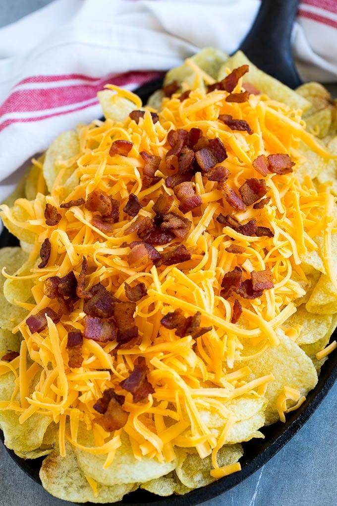Irische Nachos Rezept | Kartoffel-Nachos | Kartoffelchip-Rezept | Vorspeisen-Rezept #nachos #kartoffeln #käse #speck #vorspeise #ahurt Kesselchips mit geriebenem Käse und Speck belegt.