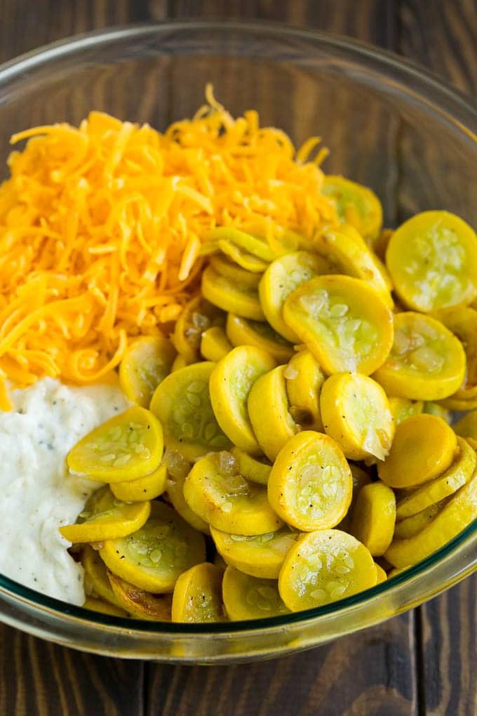 Kürbisauflauf Rezept | Gemüseauflauf | Zucchini Auflauf #auflauf #kürbis #zucchini #käse #beilage #abendessenimzoo Gekochter gelber Kürbis, cremige Soße und Cheddar-Käse in einer Rührschüssel.
