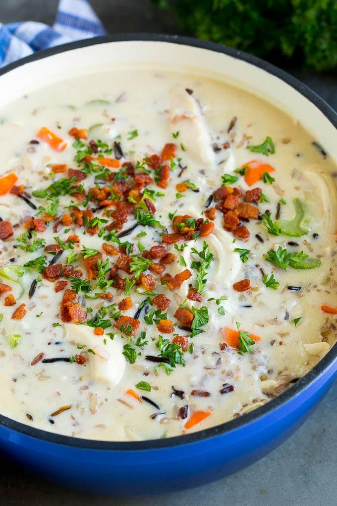 Ein Topf mit cremiger Hähnchen-Wildreis-Suppe mit Gemüse und Speck.