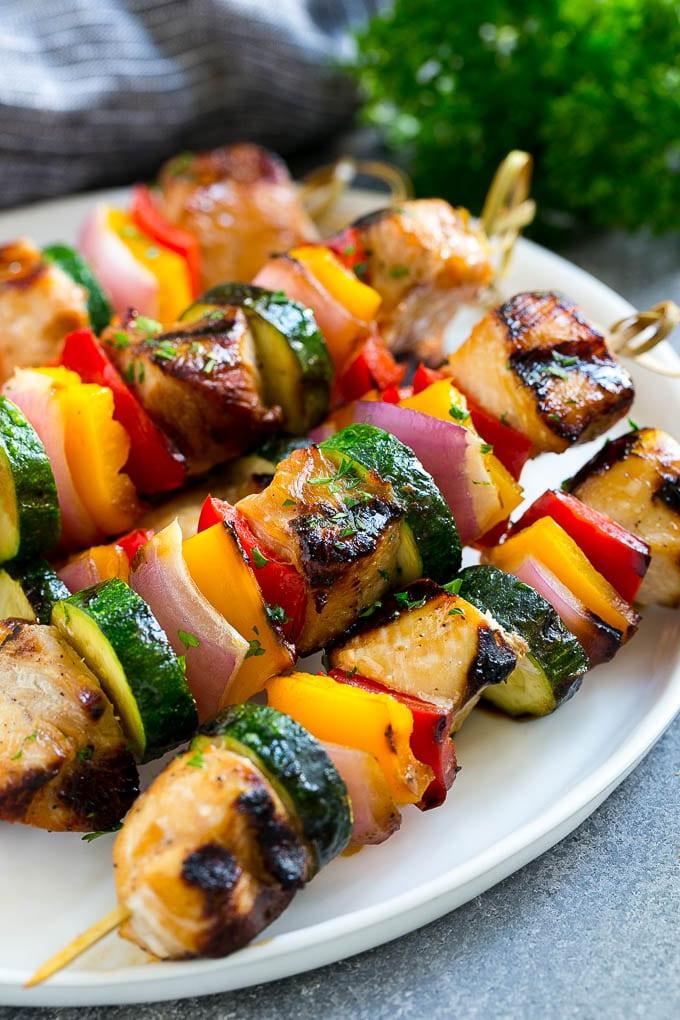 Ein Teller mit gegrillten Hähnchenspießen, zubereitet mit mariniertem Hähnchen und farbenfrohem Gemüse.