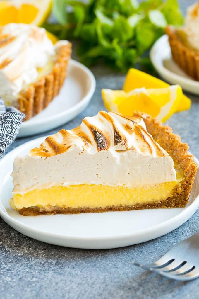 Ein Stück Zitronen-Baiser-Tarte mit cremiger Zitronenfüllung und braunem Zucker Baiser-Topping.