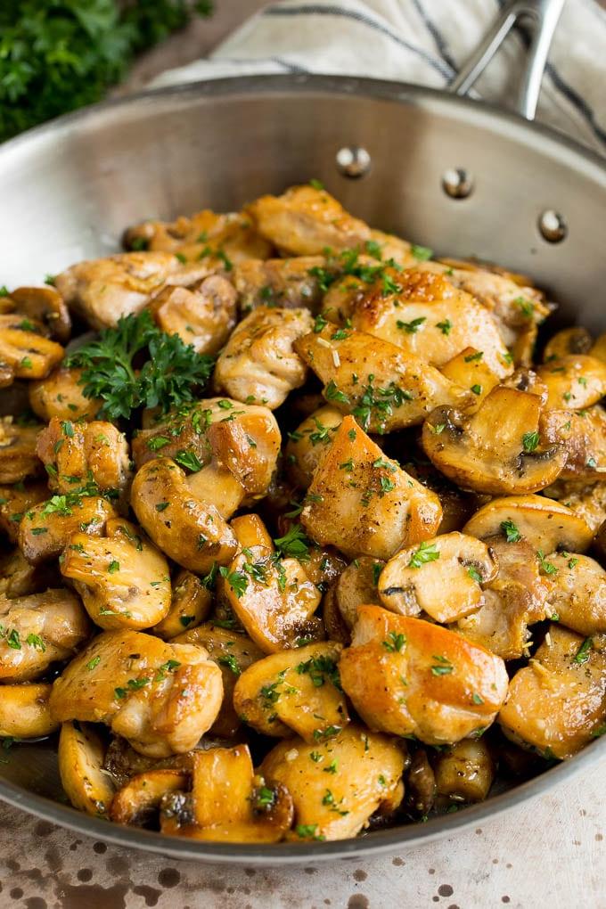 Knoblauch-Butter-Hähnchen und Champignons, mit frischer Petersilie garniert, fertig zum Servieren.