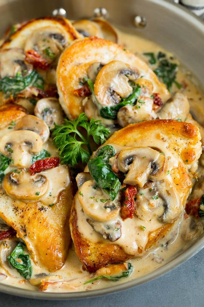 Eine Pfanne voll mit toskanischem Hähnchen, übergossen mit cremiger Pilz- und Spinatsoße.