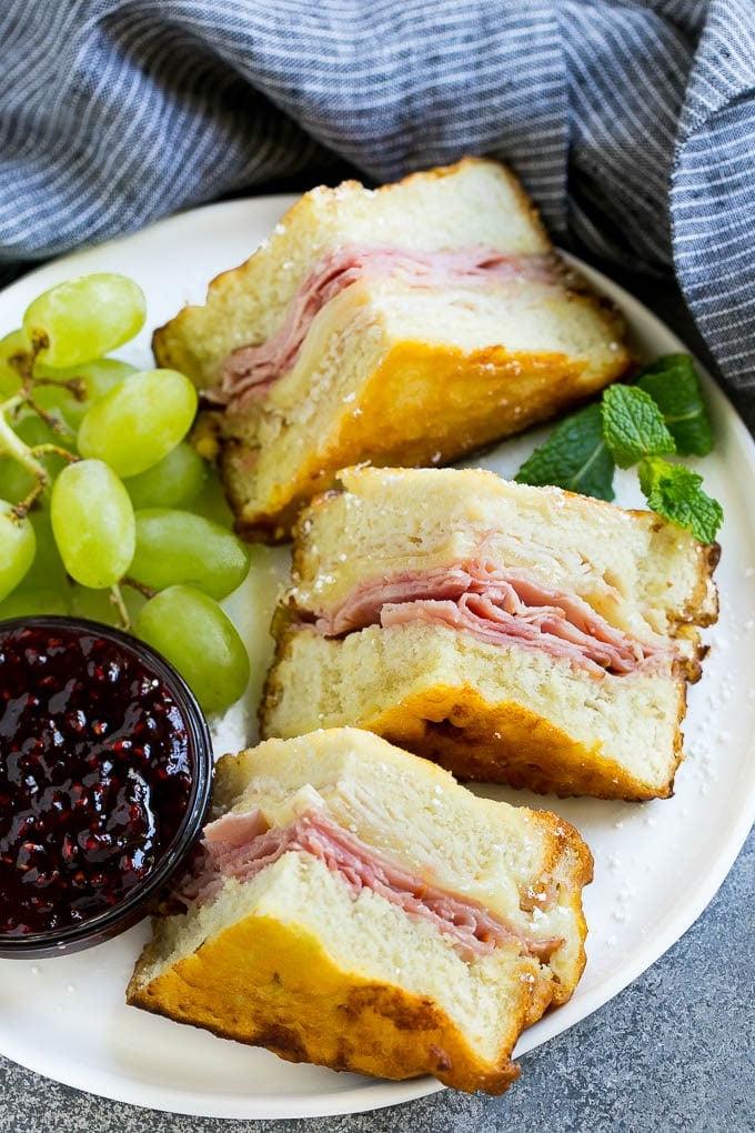 Ein Teller Monte Cristo Sandwich, serviert mit frischem Obst und Himbeermarmelade zum Dippen. Perfektes süß-herzhaftes Mittagessen.