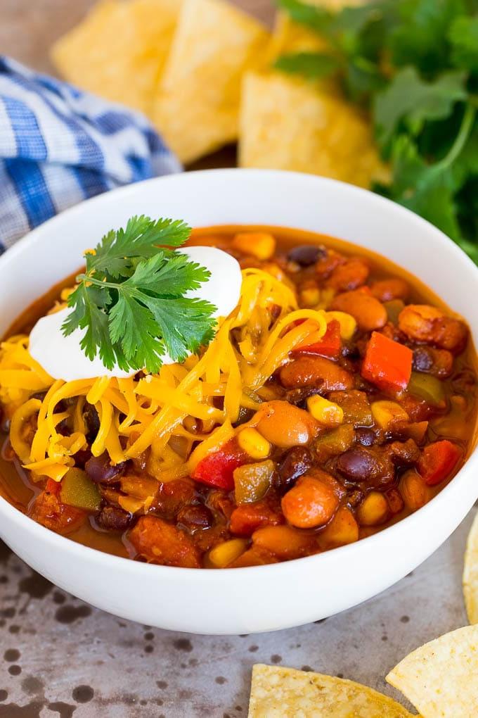 Eine dampfende Schale vegetarisches Chili, großzügig belegt mit geriebenem Käse und einem Klecks Sauerrahm.