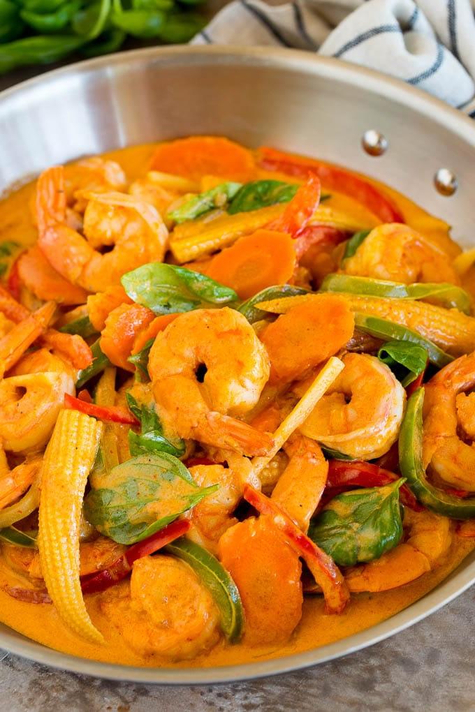 Eine Pfanne mit Garnelen-Curry, verschiedenen Gemüsesorten und frischem Basilikum.