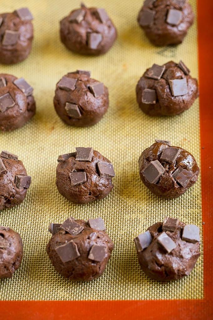 Brownie Cookies Rezept | Schokoladenkekse #kekse #brownies #schokolade #dessert #backen #abendessenimzoo Kugeln aus Keksteig mit Schokoladenstücken obenauf, bereit zum Backen.