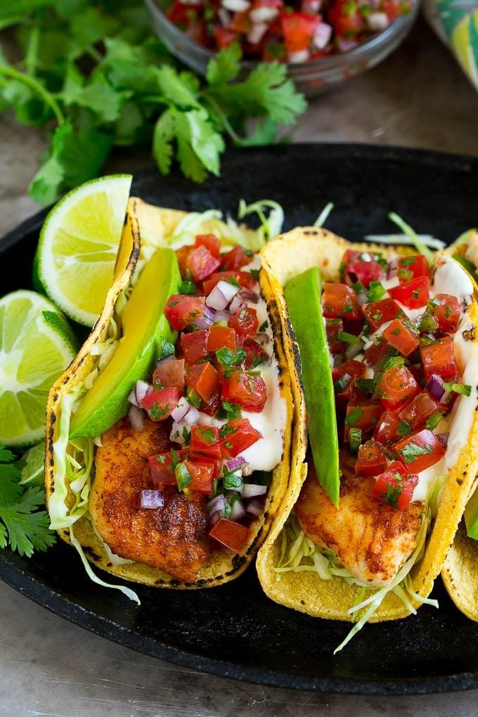 Mais-Tortillas in Fisch-Tacos gewickelt mit Avocadoscheiben und Pico de Gallo.