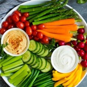 Eine große Gemüseplatte mit verschiedenen frischen und gedämpften Gemüsesorten, Ranch-Dip und Hummus.