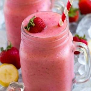 Ein Einmachglas mit einem Erdbeer-Bananen-Smoothie mit frischer Erdbeere obenauf.