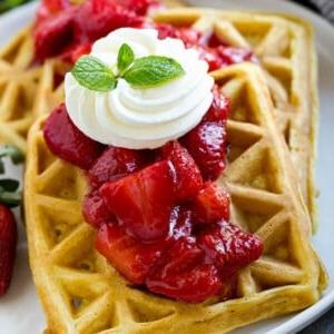 Erdbeerwaffeln sind hausgemachte Waffeln, belegt mit frischer Erdbeersauce und Schlagsahne.
