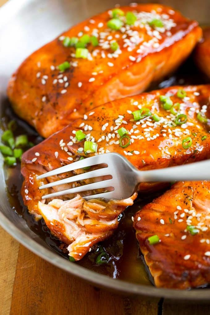 Ein Lachs Teriyaki Filet, in das mit einer Gabel geschnitten wird, um die zarte Textur zu zeigen.
