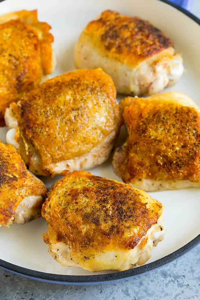 Browned chicken thighs in a pan.