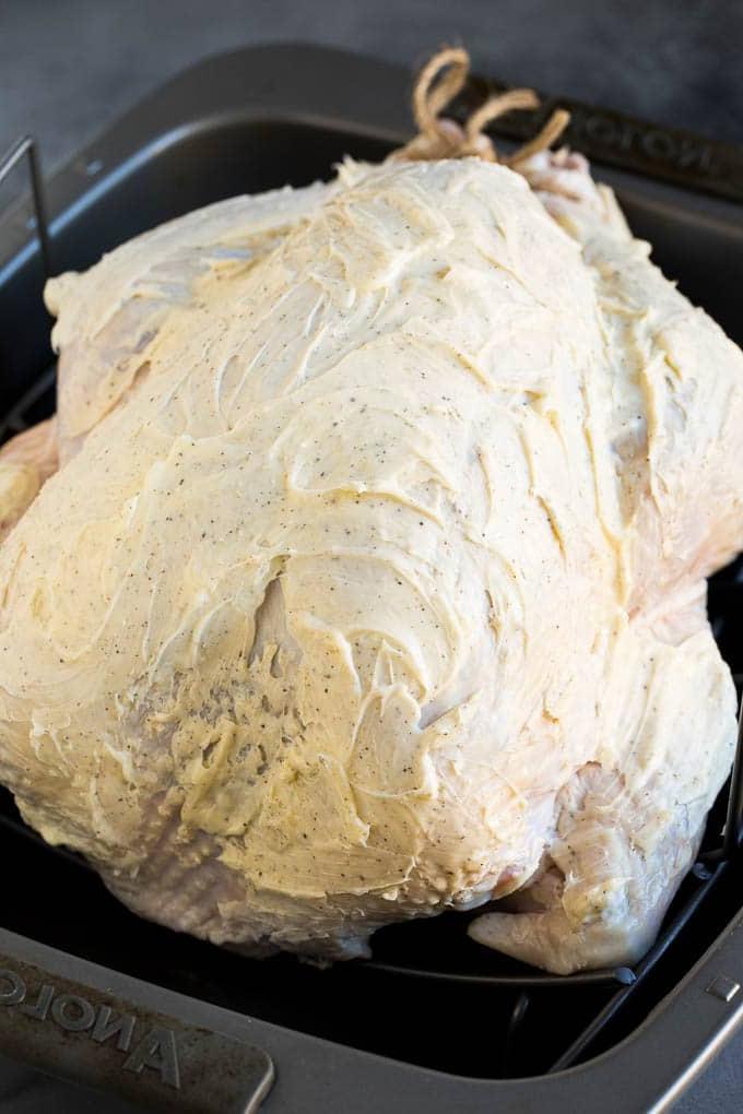 Ein umfassender Leitfaden zur Zubereitung eines Truthahns. Ein roher Truthahn, der mit gewürzter Butter bestrichen ist.