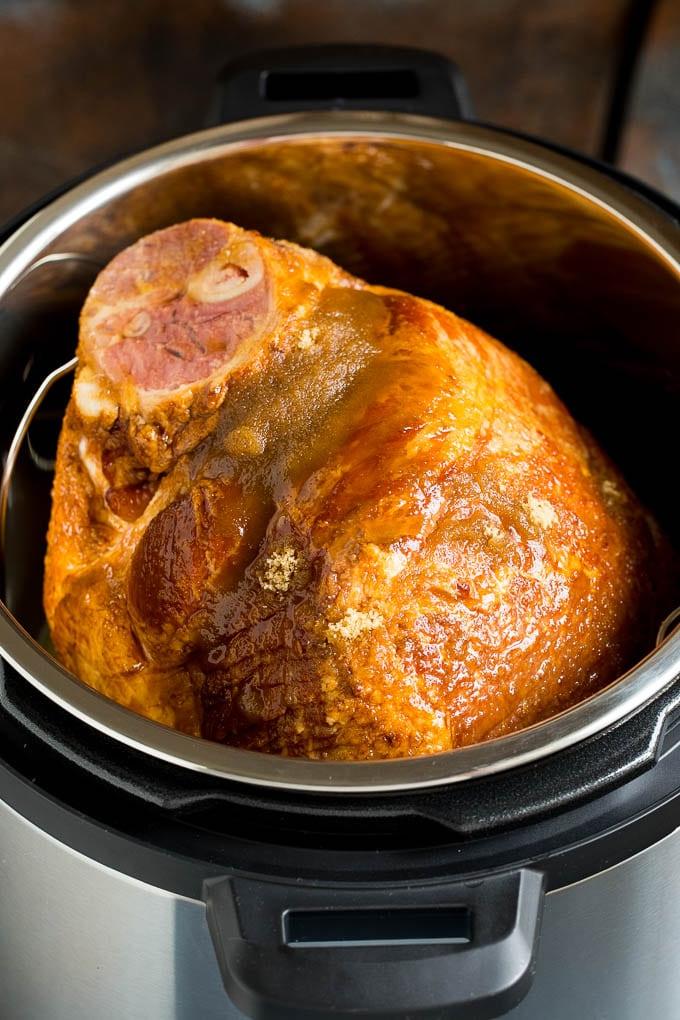 Dieser Instant Pot Schinken ist ein Spiral-Schinken, der mit einer 3-Zutaten-Glasur überzogen und dann im Schnellkochtopf zu zarter Perfektion gegart wird. Ein mit braunem Zucker und Ahornsirup überzogener Schinken in einem Instant Pot.