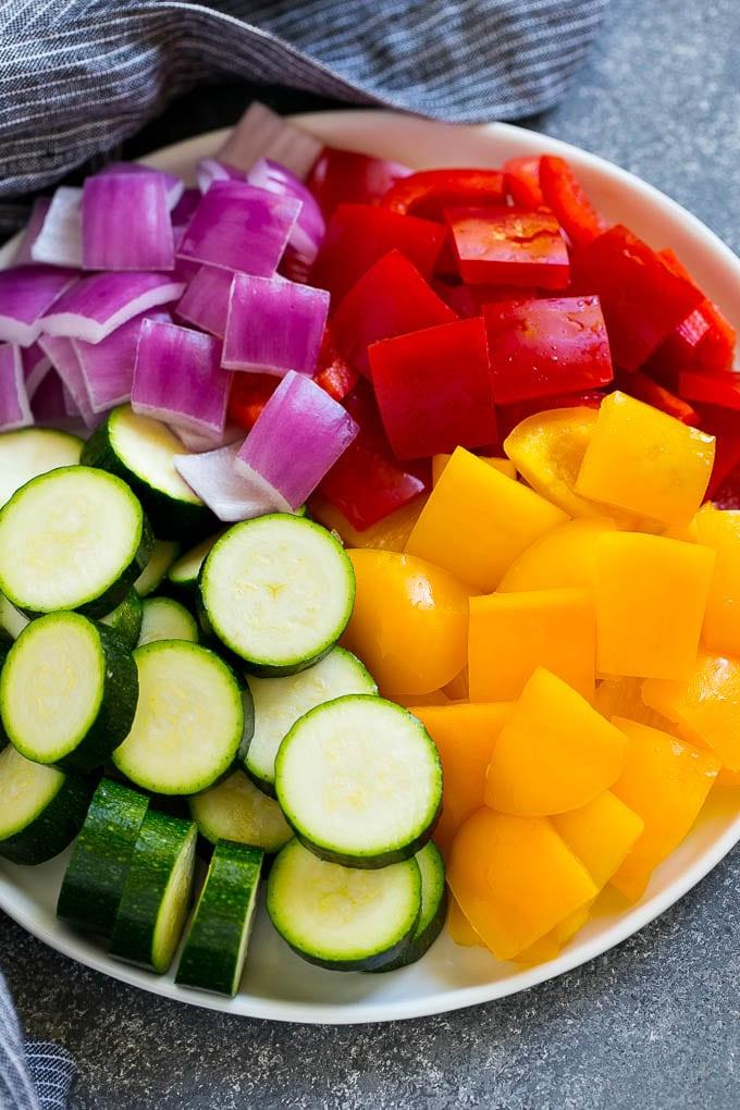 Zucchini, rote Paprika, gelbe Paprika und rote Zwiebel für gegrillte Hähnchenspieße.